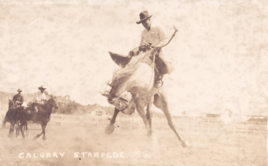 Sepia photograph of a man riding a bucking bronco horse.